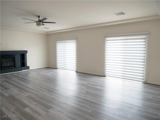 unfurnished living room with a glass covered fireplace, a healthy amount of sunlight, visible vents, and ceiling fan