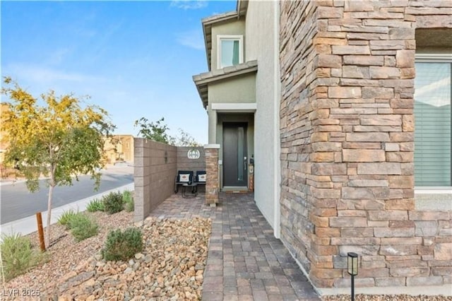 entrance to property featuring stone siding and stucco siding