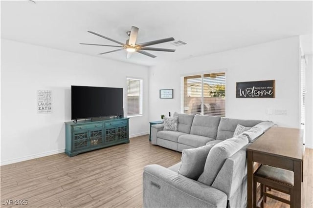 living area featuring visible vents, baseboards, a ceiling fan, and wood finished floors