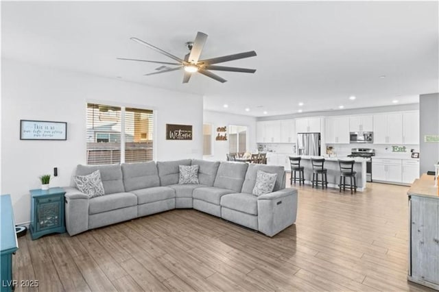 living room with light wood-style flooring, recessed lighting, and a ceiling fan