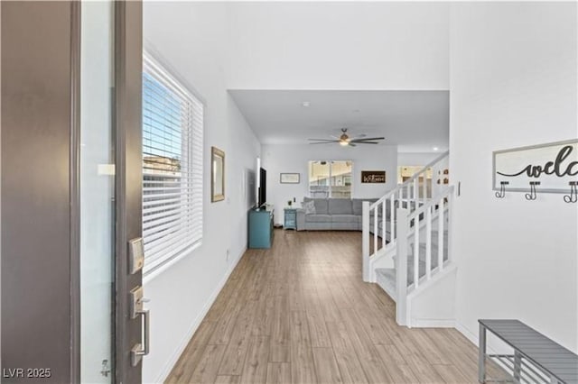 hallway featuring stairway, baseboards, and light wood finished floors