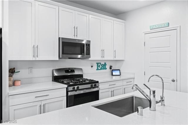 kitchen featuring light countertops, white cabinets, appliances with stainless steel finishes, and a sink