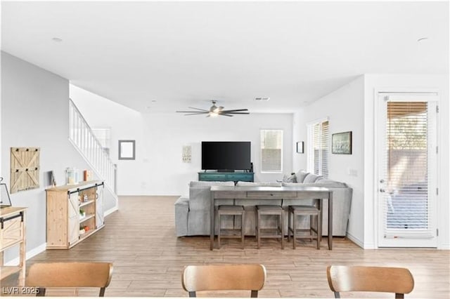 living area featuring a ceiling fan, wood finished floors, and a wealth of natural light