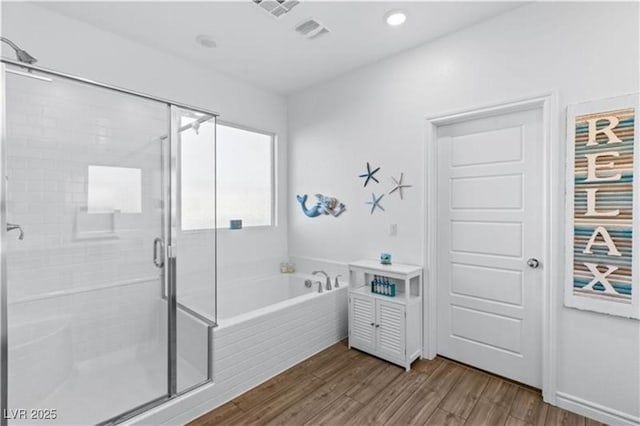 bathroom featuring a garden tub, wood finished floors, and a stall shower