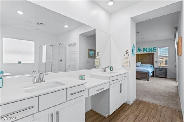 ensuite bathroom with visible vents, vanity, a stall shower, wood finished floors, and ensuite bath