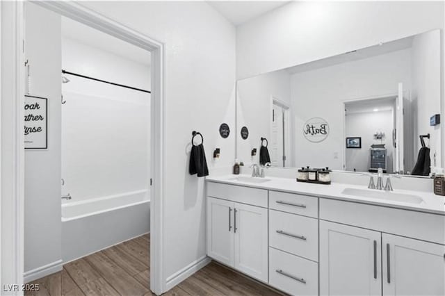 bathroom with double vanity, wood finished floors, and a sink