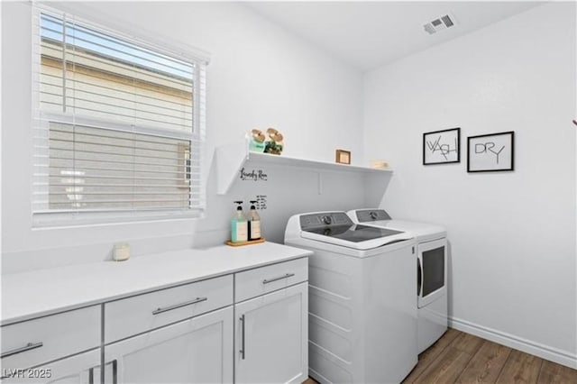 laundry area featuring visible vents, independent washer and dryer, wood finished floors, cabinet space, and baseboards