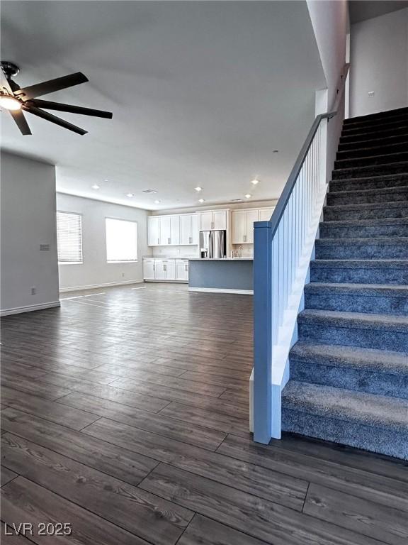 stairs featuring wood finished floors, ceiling fan, baseboards, and recessed lighting