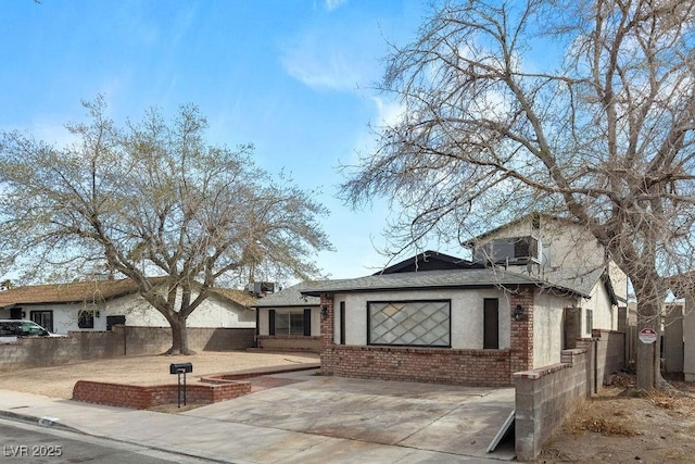 view of front of house with a patio, fence, roof with shingles, stucco siding, and brick siding