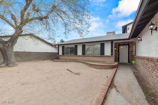 ranch-style home featuring stucco siding, brick siding, and a shingled roof