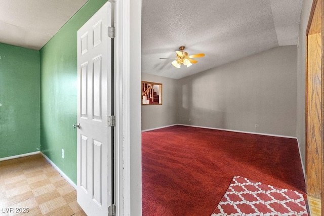 unfurnished room featuring lofted ceiling, a ceiling fan, a textured ceiling, carpet, and baseboards