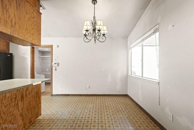 unfurnished dining area with a notable chandelier, light floors, and baseboards