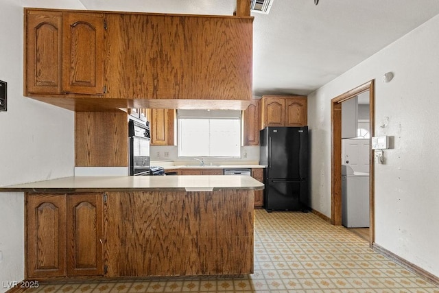 kitchen with brown cabinetry, visible vents, washer / dryer, a peninsula, and freestanding refrigerator