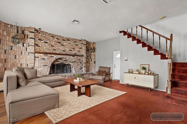 living area featuring stairs, a fireplace, and visible vents