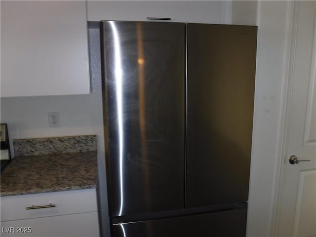details with white cabinetry, light stone counters, and freestanding refrigerator