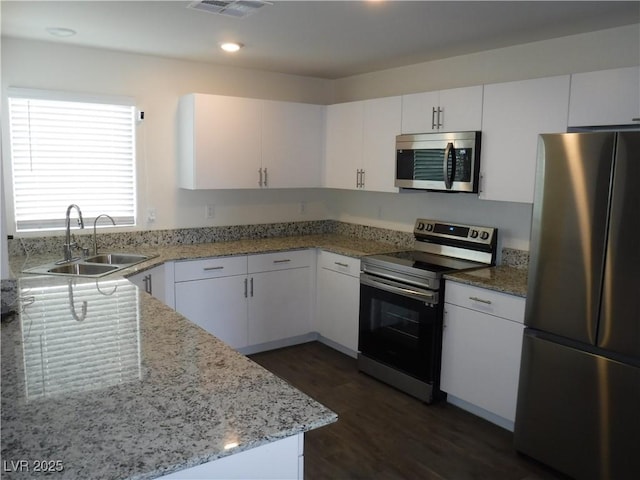 kitchen featuring a sink, white cabinetry, stainless steel appliances, visible vents, and dark wood-style flooring