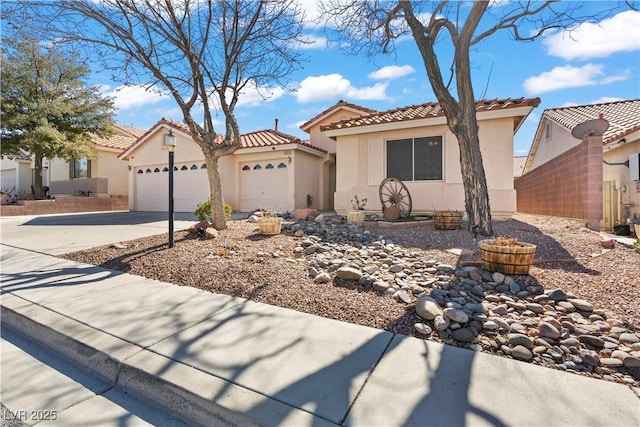 mediterranean / spanish house featuring concrete driveway, a tiled roof, a garage, and stucco siding