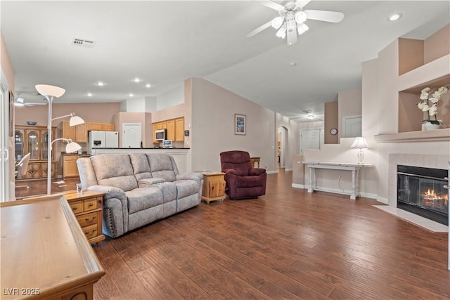 living room featuring visible vents, dark wood finished floors, a fireplace, ceiling fan, and vaulted ceiling