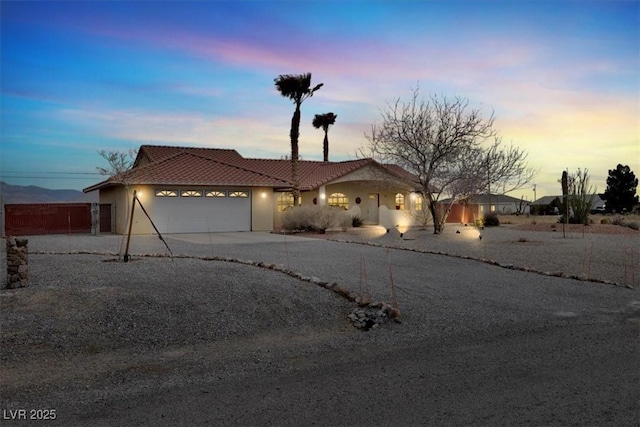 view of front of property featuring fence, a tiled roof, concrete driveway, stucco siding, and a garage