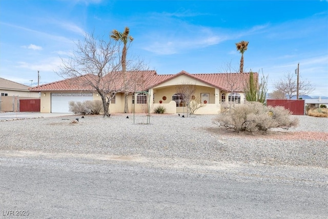 view of front facade featuring fence, an attached garage, stucco siding, concrete driveway, and a tiled roof