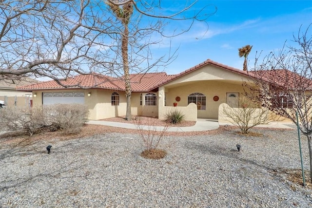 view of front of house featuring stucco siding, a tiled roof, and a garage