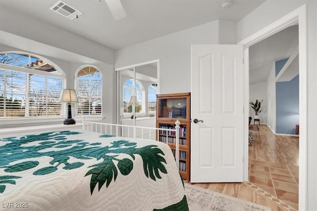 bedroom with ceiling fan, visible vents, a closet, and wood finished floors