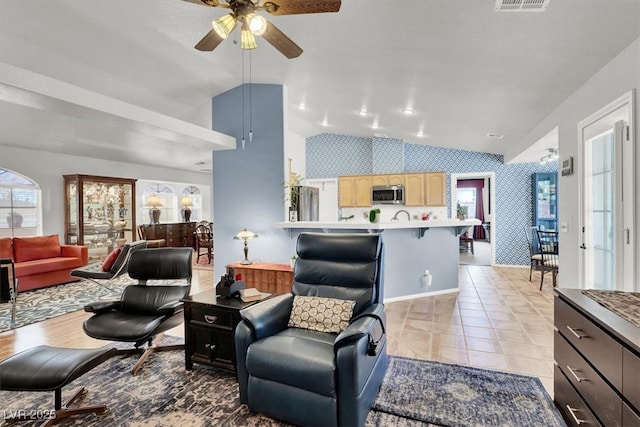 living area with visible vents, light tile patterned flooring, wallpapered walls, lofted ceiling, and ceiling fan