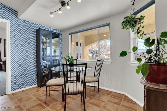 dining room featuring baseboards, wallpapered walls, rail lighting, an accent wall, and tile patterned floors