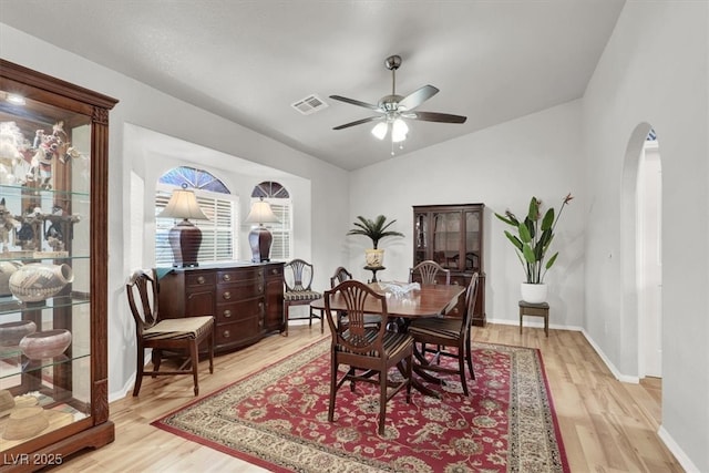 dining space with visible vents, light wood-style flooring, a ceiling fan, and vaulted ceiling