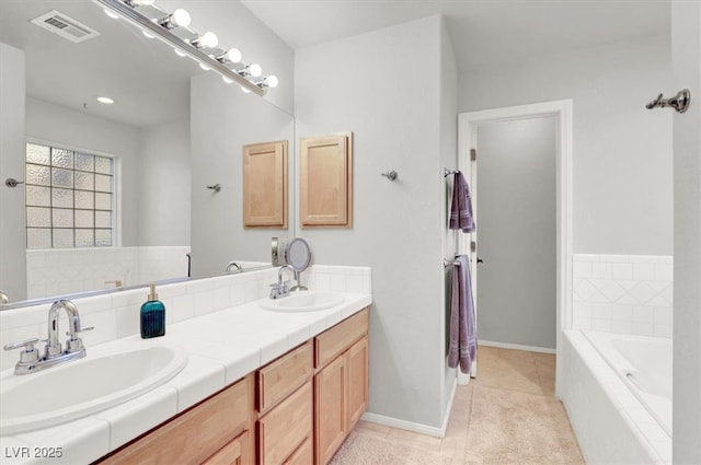 full bath featuring tiled bath, visible vents, tile patterned flooring, and a sink