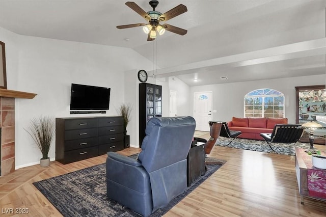 living room featuring light wood-style flooring, baseboards, a fireplace, lofted ceiling, and ceiling fan