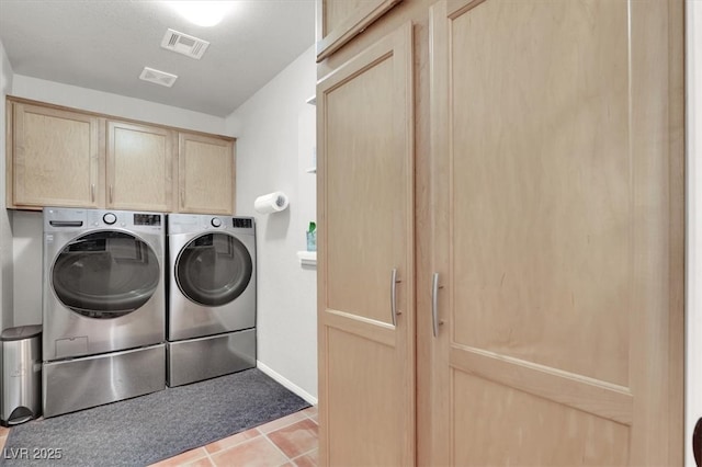 clothes washing area with washing machine and dryer, cabinet space, visible vents, and baseboards