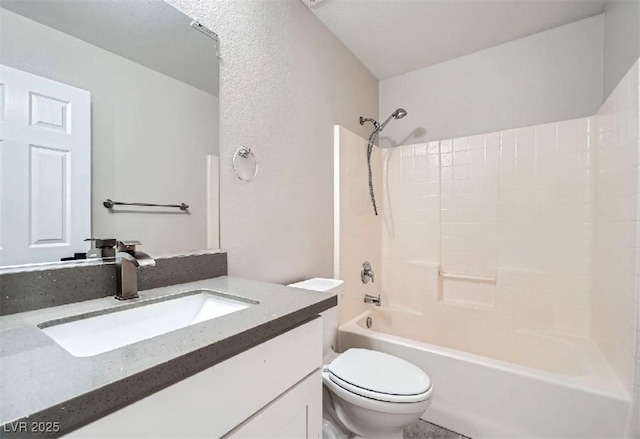 full bath with tub / shower combination, toilet, vanity, and a textured wall