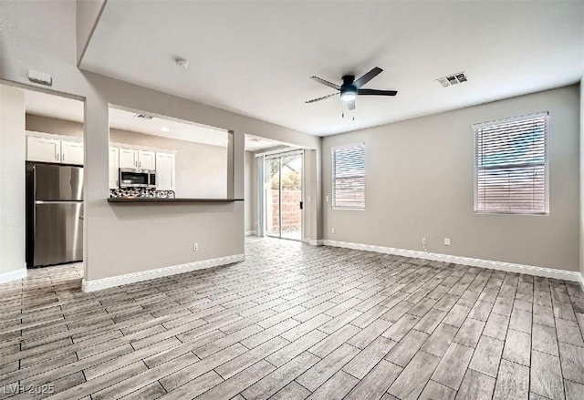 unfurnished living room featuring visible vents, light wood-style flooring, baseboards, and a ceiling fan