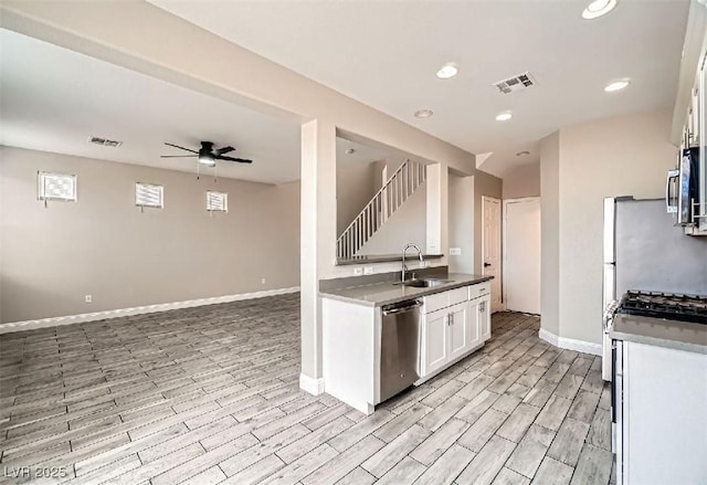 kitchen featuring visible vents, wood finish floors, a sink, appliances with stainless steel finishes, and white cabinetry