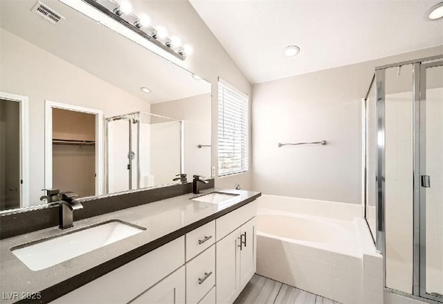 full bathroom with vaulted ceiling, a shower stall, and a sink