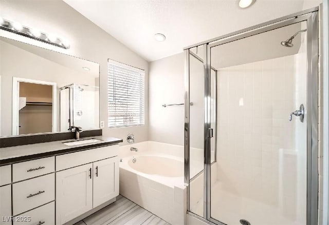 bathroom with a garden tub, a stall shower, vanity, lofted ceiling, and a spacious closet