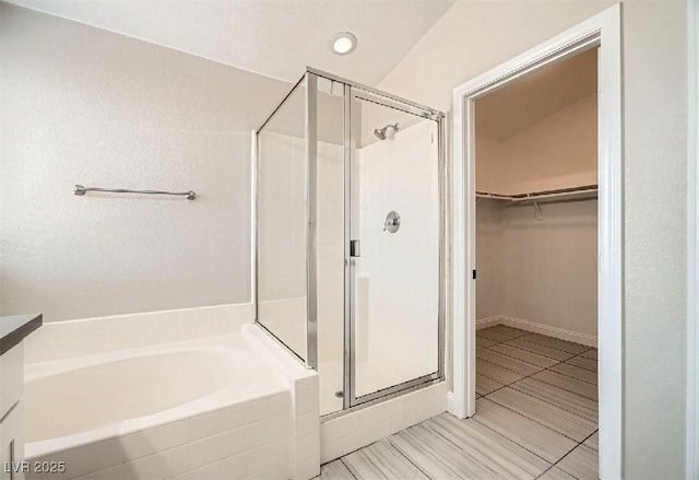 bathroom with a walk in closet, a shower stall, and a bath