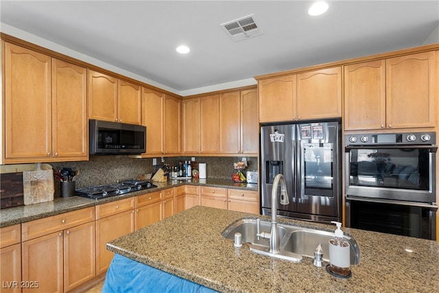 kitchen with gas cooktop, light stone countertops, visible vents, double wall oven, and stainless steel fridge