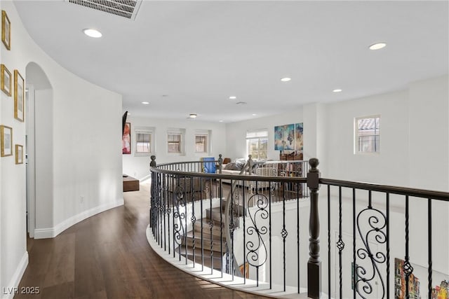 hall with an upstairs landing, visible vents, a wealth of natural light, and wood finished floors