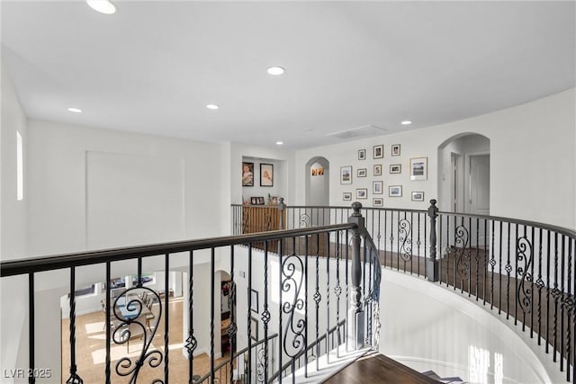 hall with visible vents, an upstairs landing, recessed lighting, and arched walkways