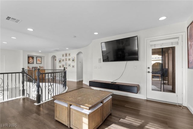 living room with dark wood-style floors, recessed lighting, arched walkways, and visible vents