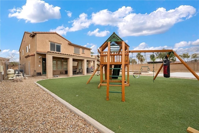 view of playground featuring a patio area, a yard, and fence