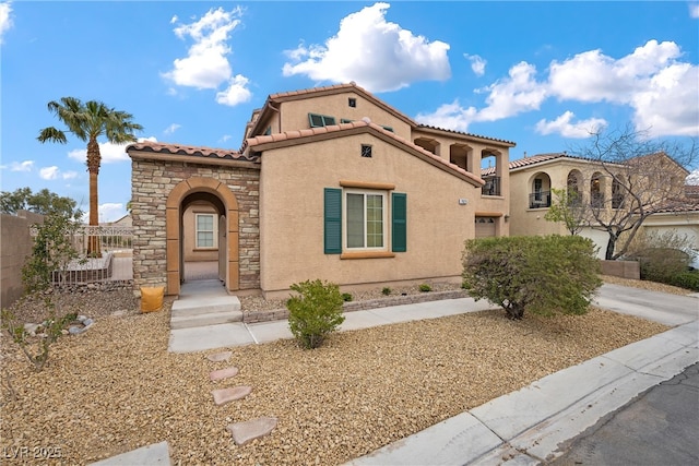 mediterranean / spanish-style house featuring stucco siding, driveway, stone siding, fence, and a tiled roof