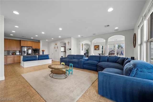 living room featuring arched walkways, visible vents, recessed lighting, and decorative columns