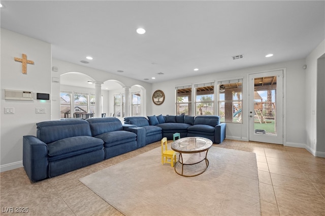 living room with light tile patterned flooring, recessed lighting, arched walkways, and ornate columns