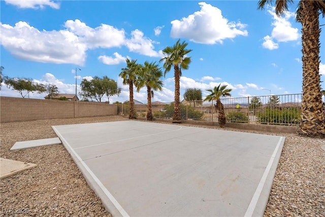 view of basketball court with basketball hoop and a fenced backyard