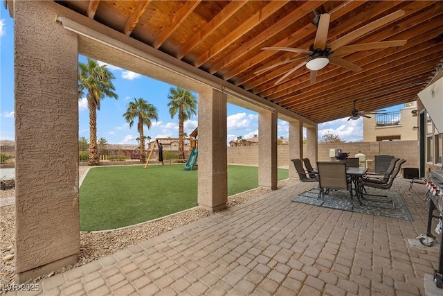 view of patio featuring ceiling fan, outdoor dining area, a fenced backyard, and a playground