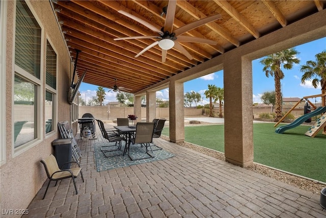 view of patio featuring a playground, outdoor dining area, a fenced backyard, and ceiling fan