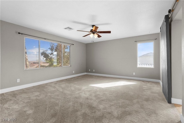 carpeted empty room with visible vents, plenty of natural light, baseboards, and a ceiling fan